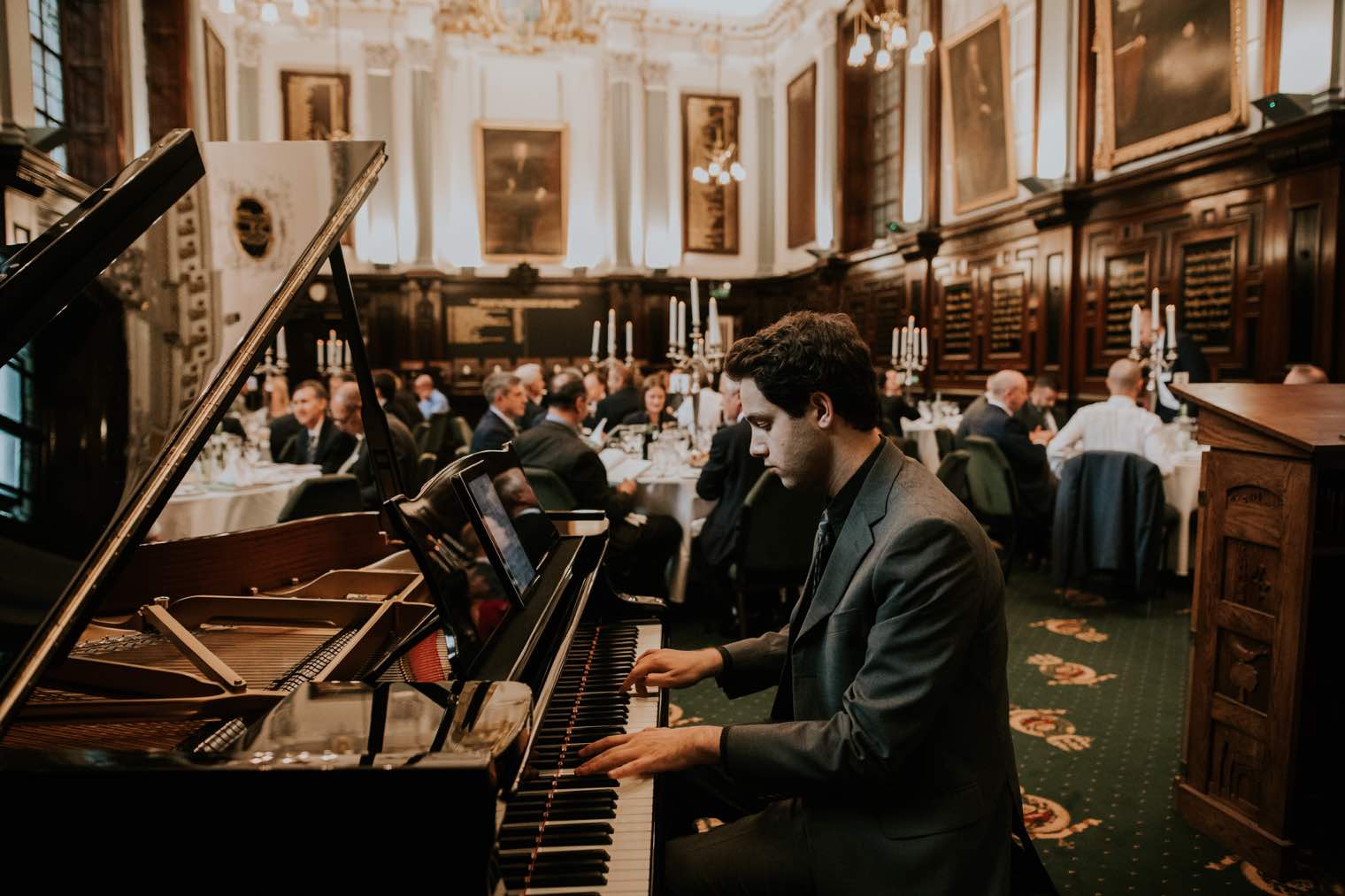 a man playing a piano to a wedding crowd in Merchants House, Glasgow