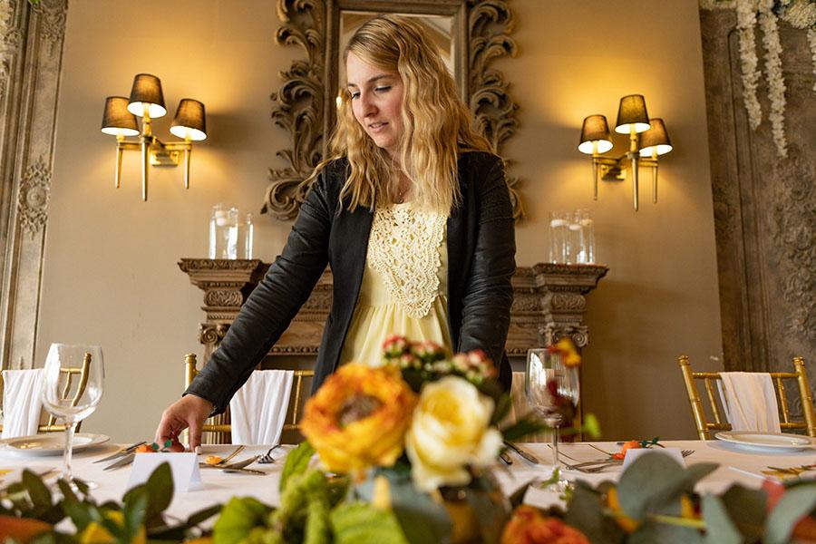 a blonde woman standing at a table preparing it for a wedding.
